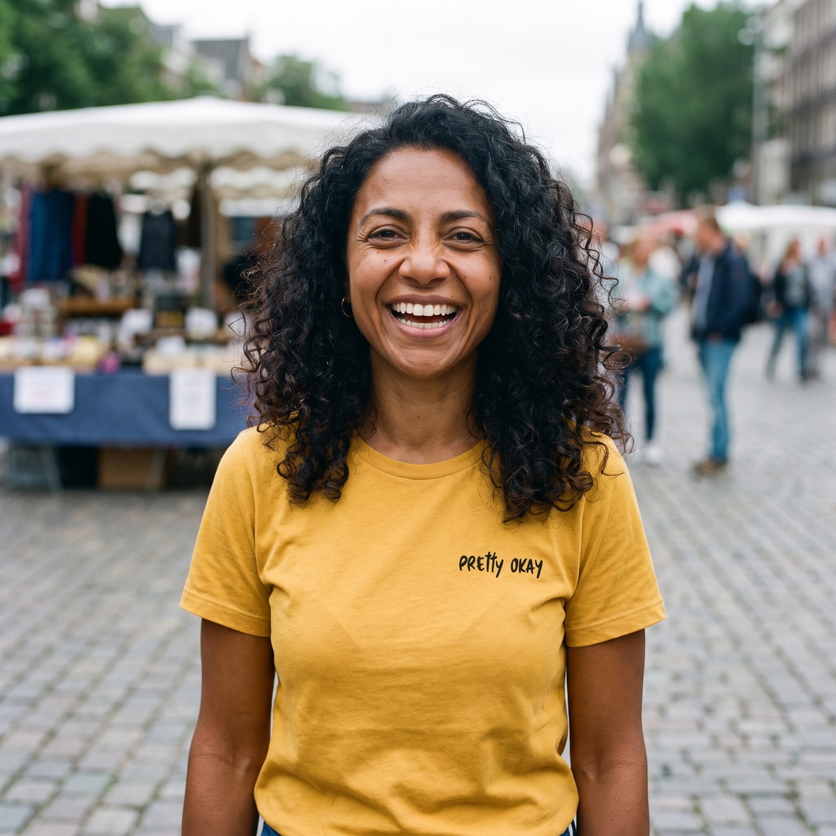 Pretty okay embroidered Finnish humour t-shirt in gold, worn by Nea on a market square, Very Finnish Problems