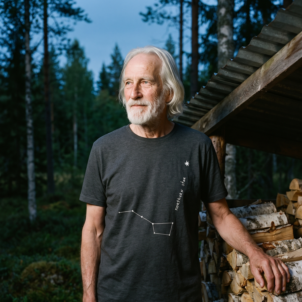 Northern Star 2 organic t-shirt in Anthracite, worn by Pertti beside a birch woodpile in the forest, Very Finnish Problems