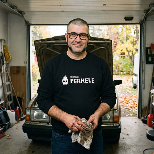 Powered by Perkele sweatshirt in black, worn by Jaska in a garage workshop, Very Finnish Problems