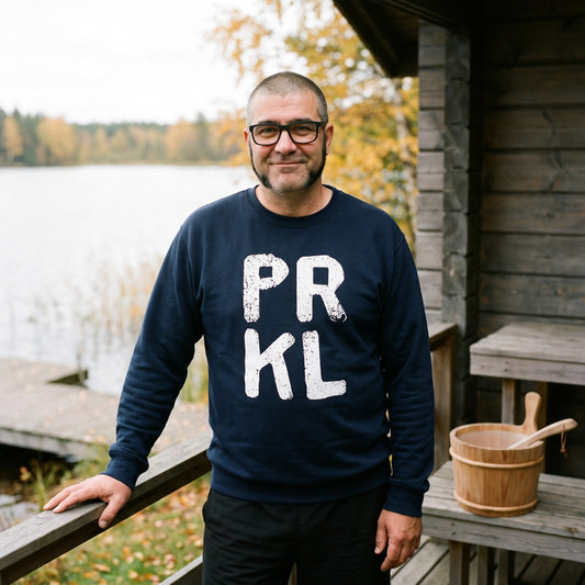 PRKL sweatshirt in navy, worn by Jaska on a lakeside sauna deck, Very Finnish Problems