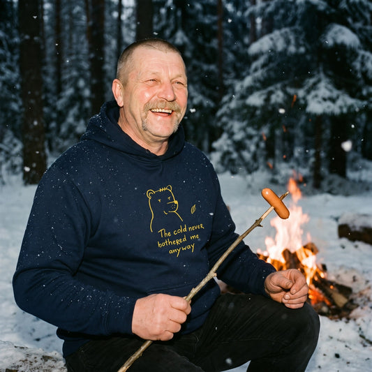 The cold never bothered me... Finnish Hoodie in navy, worn by Juha grilling sausages over a winter campfire, Very Finnish Problems