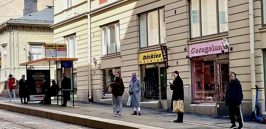 People waiting at a Helsinki tram stop, each keeping a comfortable distance from the others