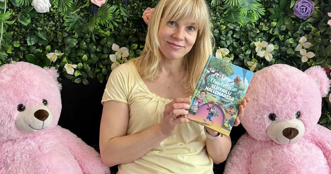 Anna Kurkijärvi-Willans holding Charlotta ja seikkailu Nallemaassa, flanked by two large pink teddy bears