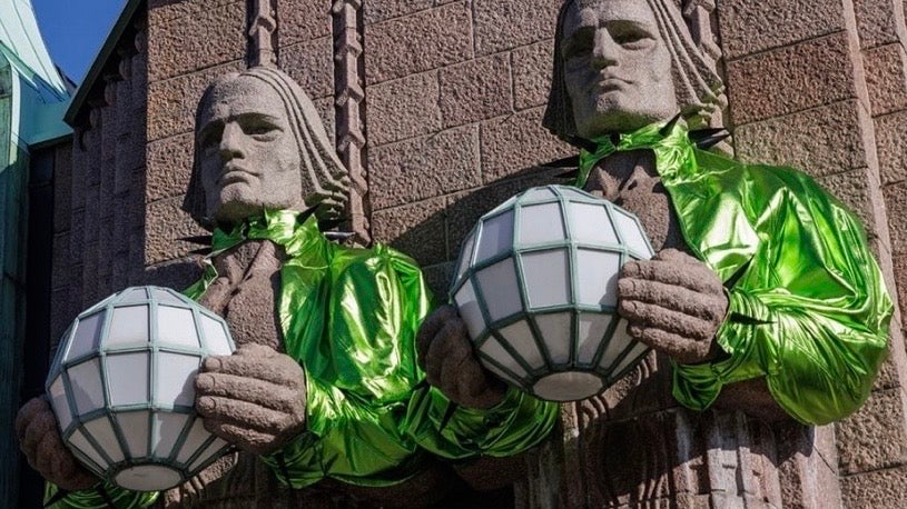 The stone lantern bearers outside Helsinki Central Station dressed in shiny green outfits
