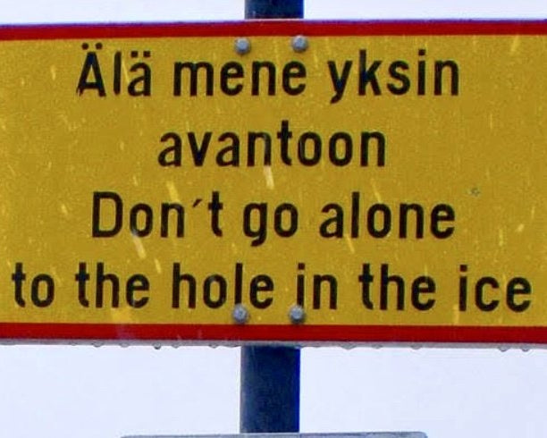 A yellow Finnish warning sign reading Ala mene yksin avantoon, do not go alone to the hole in the ice