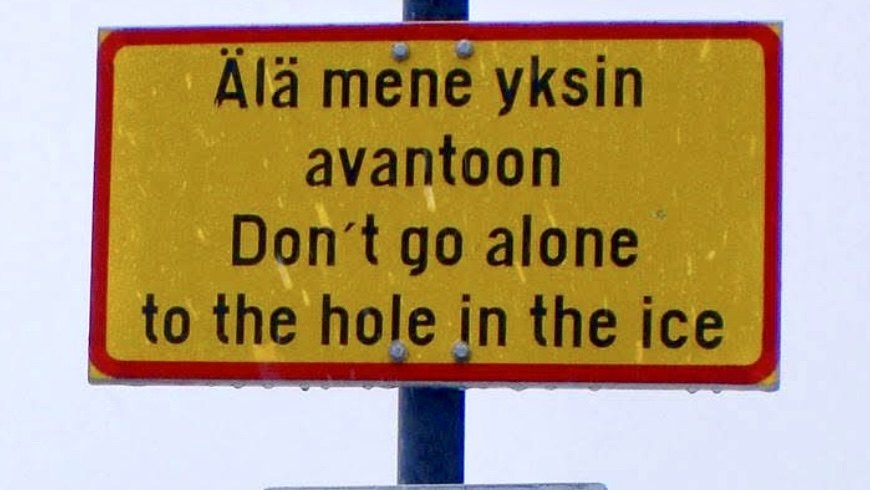 A yellow Finnish warning sign reading Ala mene yksin avantoon, Don't go alone to the hole in the ice, in both Finnish and English