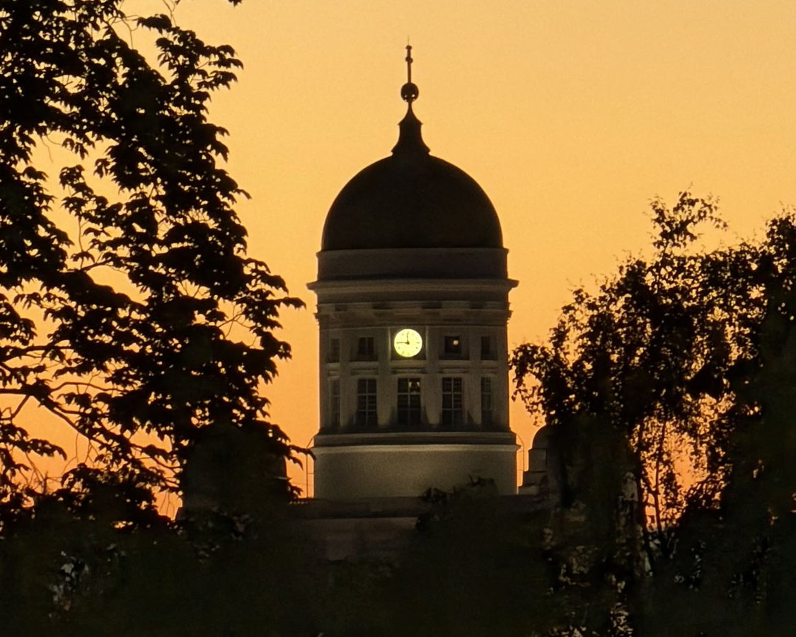 A Finnish church dome silhouetted against an orange winter sunset