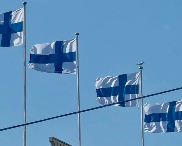 Finnish flags flying against a bright blue sky