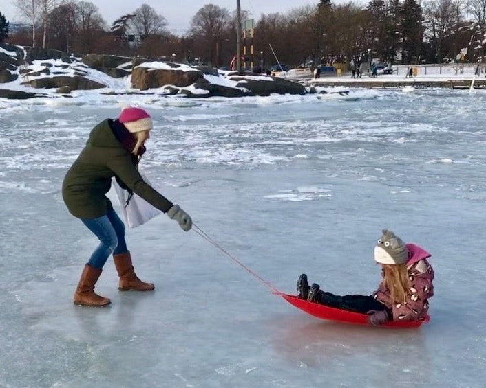 A woman pulling a small child on a sledge across the frozen sea in Helsinki