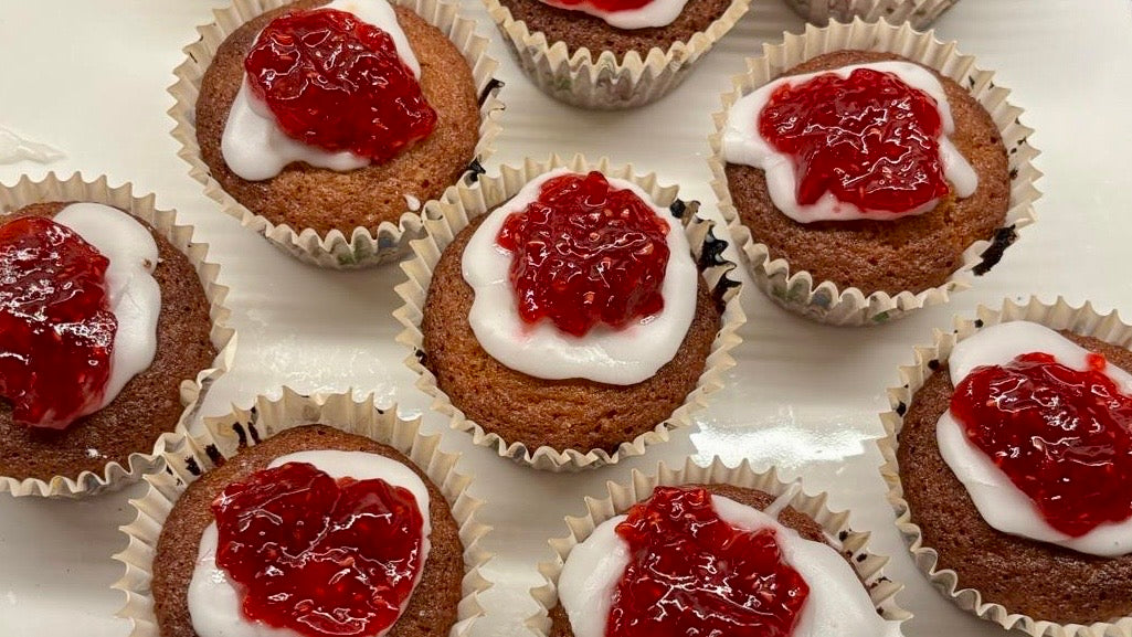 Freshly baked Runeberg cakes with white icing and raspberry jam in paper cases, photo by Joel Willans