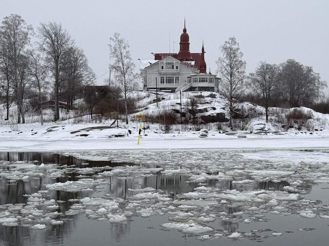 Drifting ice floes on the sea below the red-towered Klippan villa in Helsinki on a grey winter day