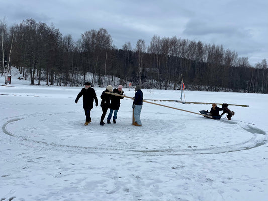 People turning a huge disc cut from the ice of a frozen Finnish lake, an ice carousel, with a passenger riding on it. Photo: Joel Willans