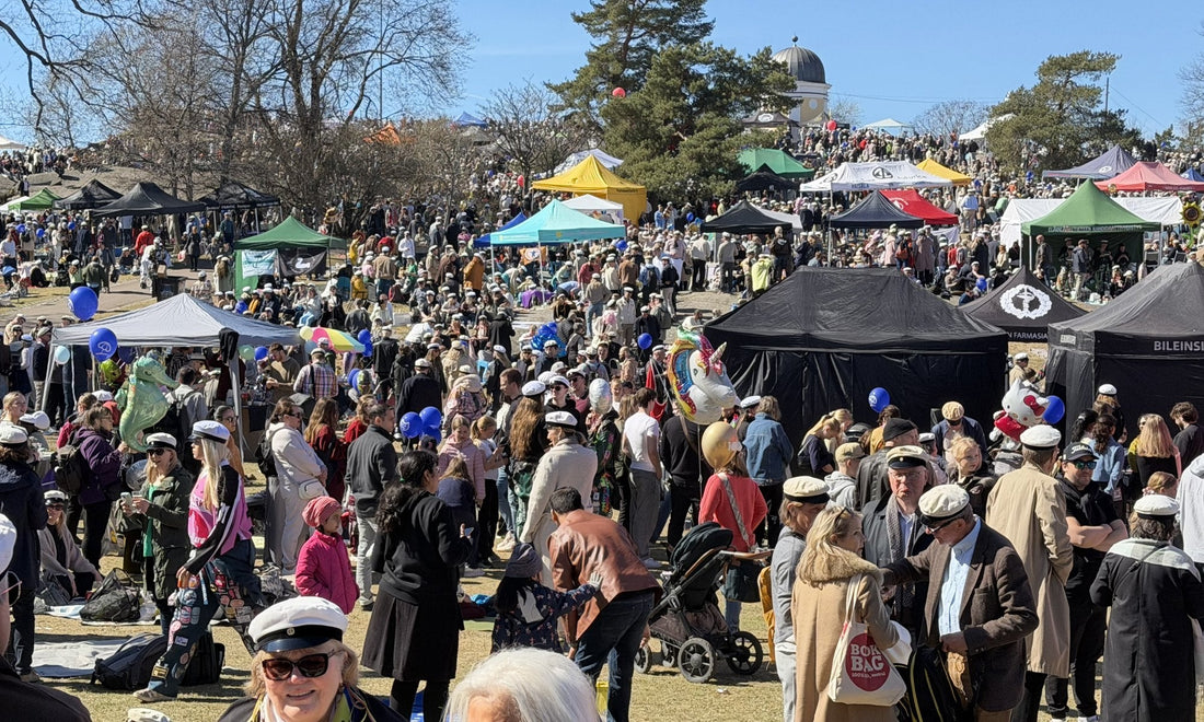 Crowds in white student caps celebrating Vappu in spring sunshine in a Helsinki park. Photo: Joel Willans