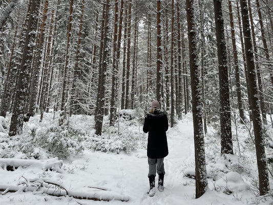 A woman walking a snow covered path through a Finnish pine forest, seen from behind. Photo: Joel Willans