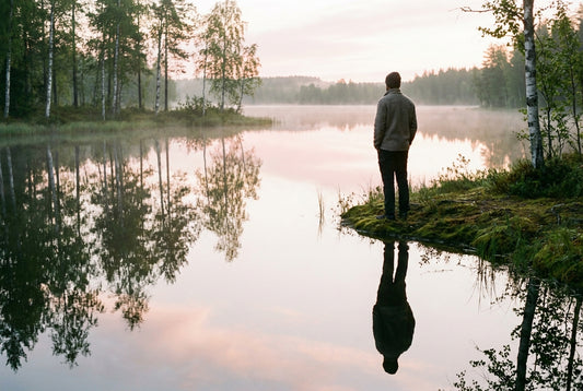 Thoughtful figure at a Finnish lake at sunrise
