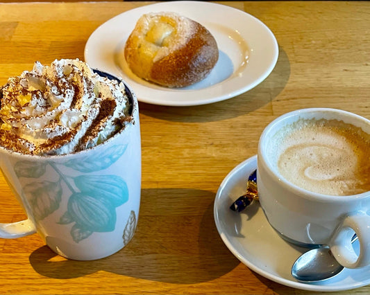 A cappuccino, a black coffee and a pulla bun on a wooden cafe table in Finland. Photo: Joel Willans