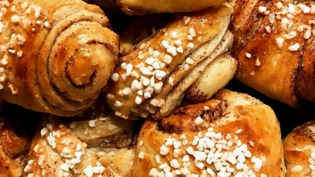 A close-up of Finnish korvapuusti cinnamon buns topped with pearl sugar.