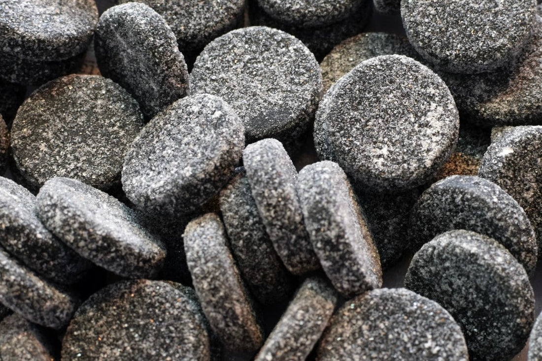 A close-up pile of Finnish salmiakki, grey salty liquorice pastilles