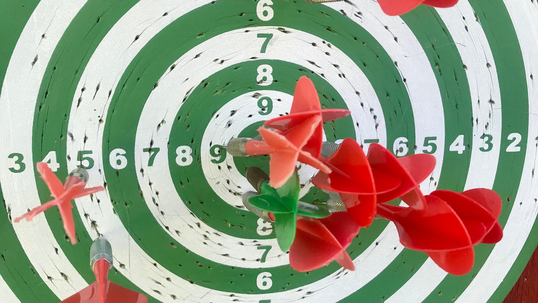 Plastic darts clustered around the bullseye of a battered green and white Finnish dartboard