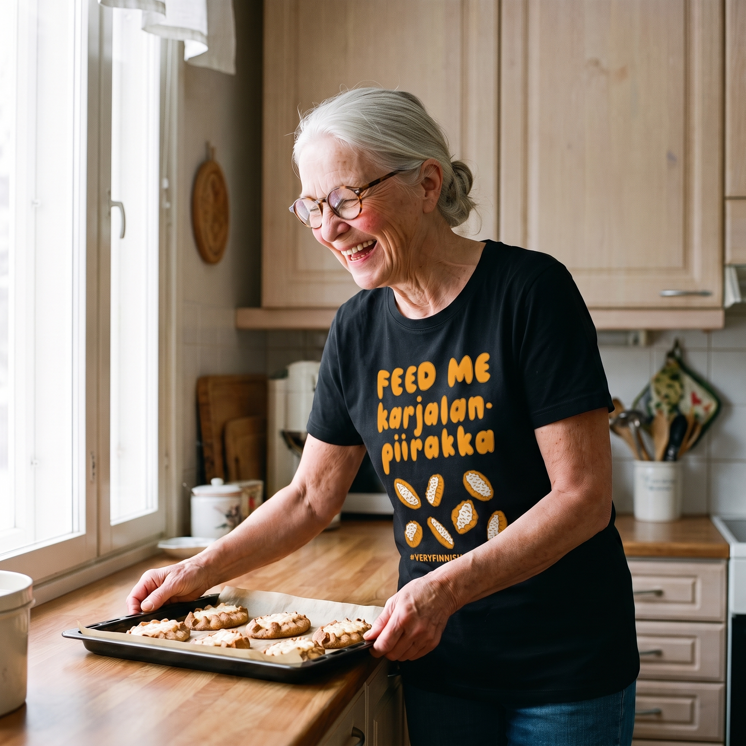 Feed Me Karjalanpiirakka t-shirt in black, worn by Raija setting down a tray of Karelian pies, Very Finnish Problems