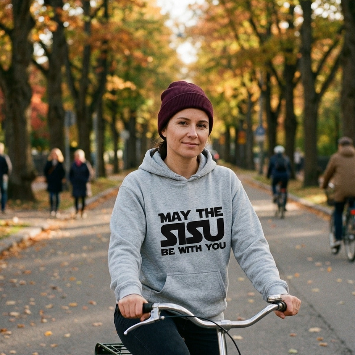 May the Sisu Be With You hoodie in sport grey, worn by a woman cycling through a Helsinki avenue in autumn, Very Finnish Problems