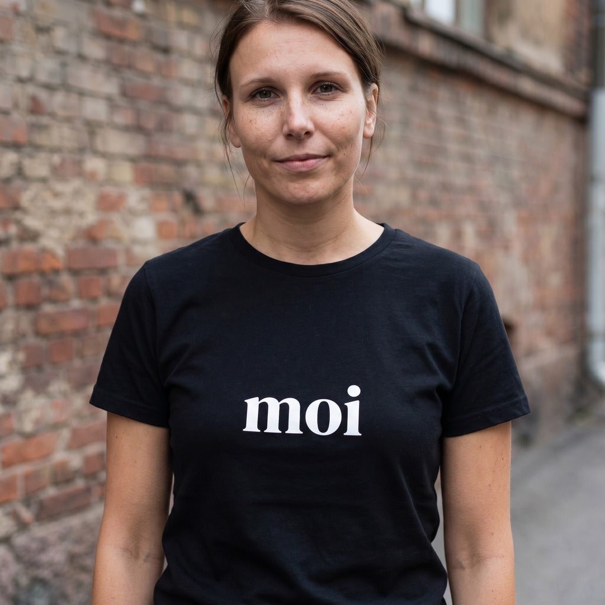 Woman on a Helsinki street wearing the black Moi Finnish greeting t-shirt