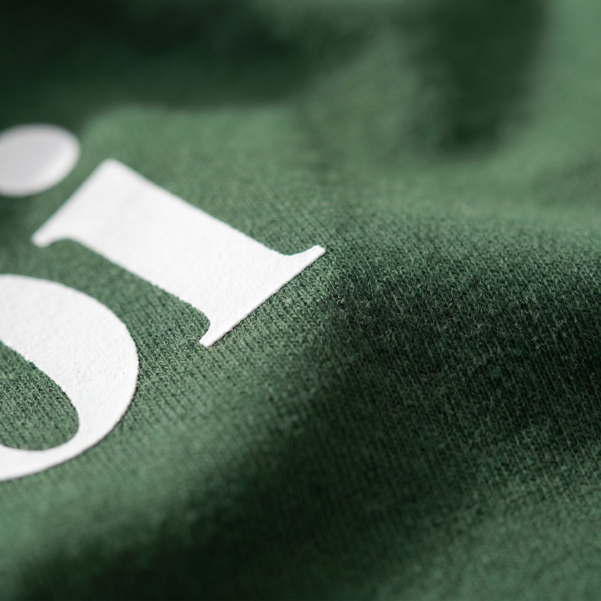 Macro close-up of the white moi serif print on forest green cotton fabric