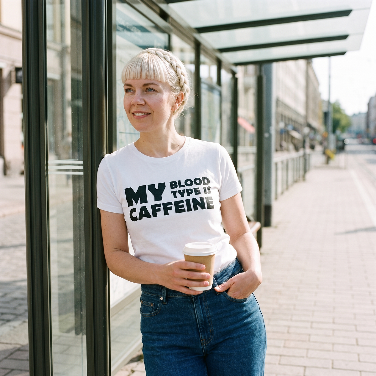 Caffeine Blood Type t-shirt in white, worn by Venla with a takeaway coffee at a Helsinki tram shelter, Very Finnish Problems