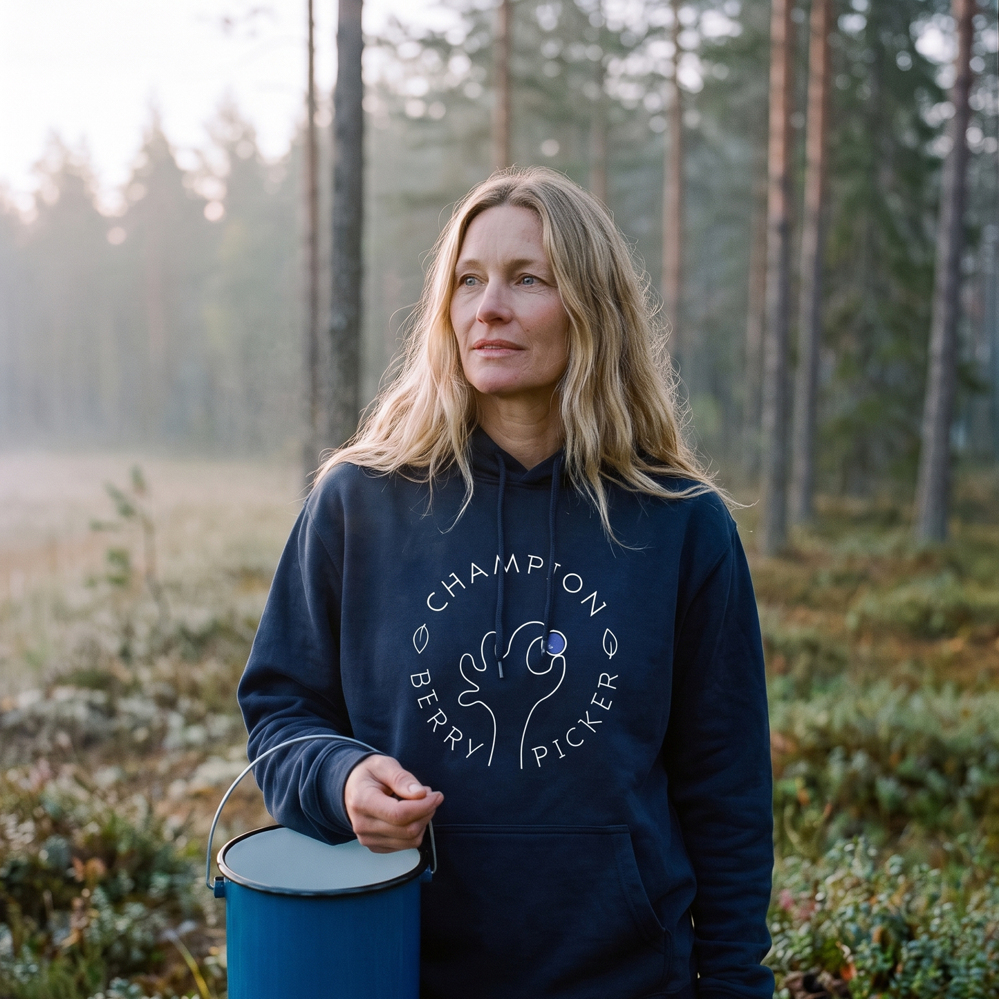 Champion Blueberry Picker hoodie in navy, worn by Elina at the edge of a misty Finnish forest at dawn, Very Finnish Problems