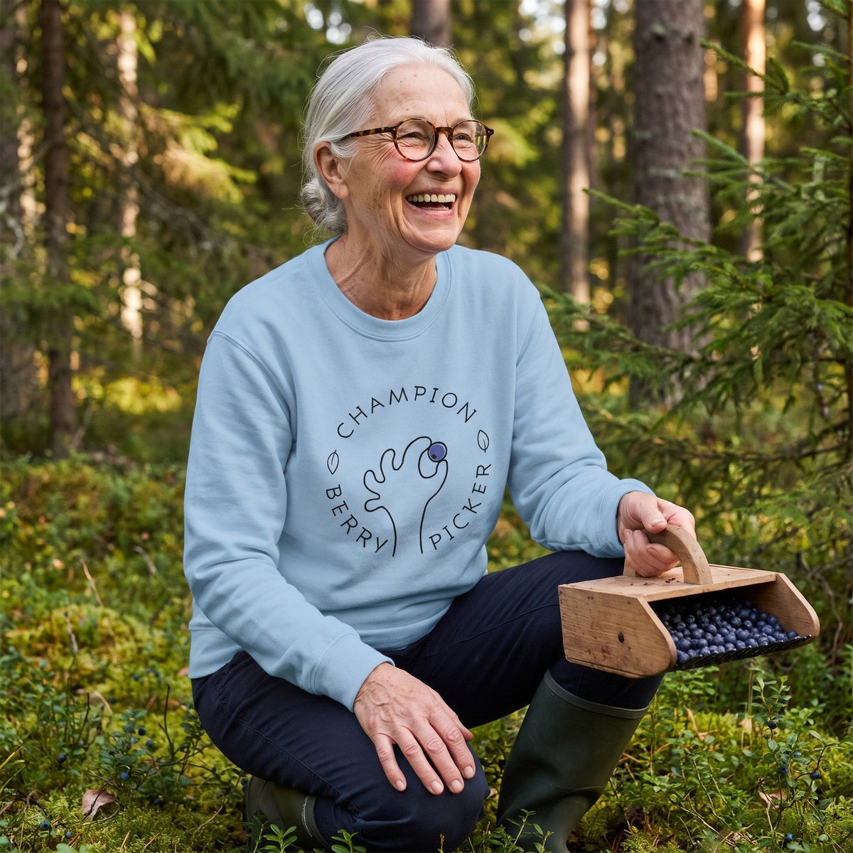 Champion Blueberry Picker sweatshirt in light blue, worn by Raija picking blueberries in a Finnish forest, Very Finnish Problems