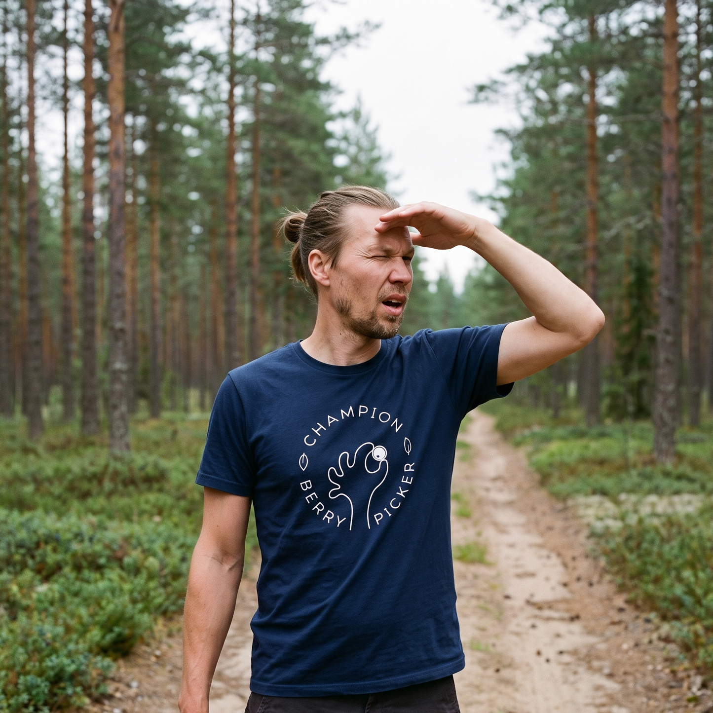 Champion Blueberry Picker t-shirt in navy, worn by Joonas with a berry picker on a Finnish forest track, Very Finnish Problems