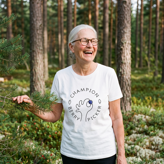 Champion Blueberry Picker t-shirt in white, worn by Raija picking wild blueberries in a Finnish pine forest, Very Finnish Problems