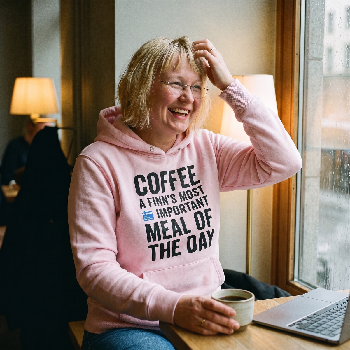 Coffee Meal of the Day hoodie in light pink, worn by Marika laughing at a rainy Helsinki cafe window, Very Finnish Problems