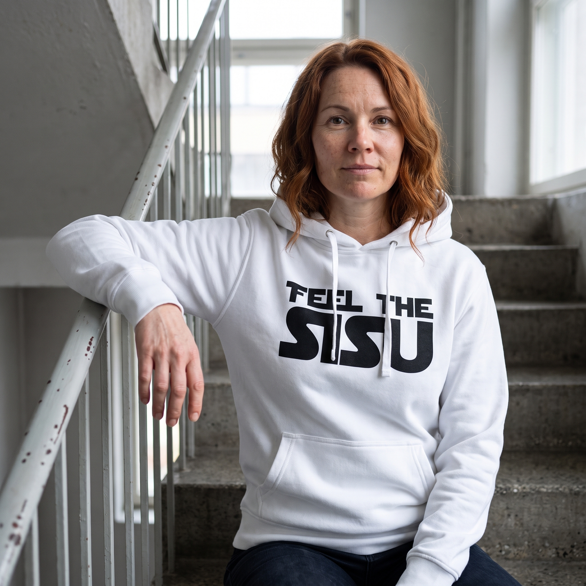 Feel the sisu Finnish culture hoodie in white, worn by Sanna on concrete stairs, Very Finnish Problems