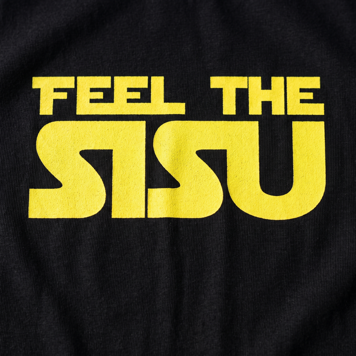Close-up of the Feel the sisu print on black t-shirt fabric, Very Finnish Problems