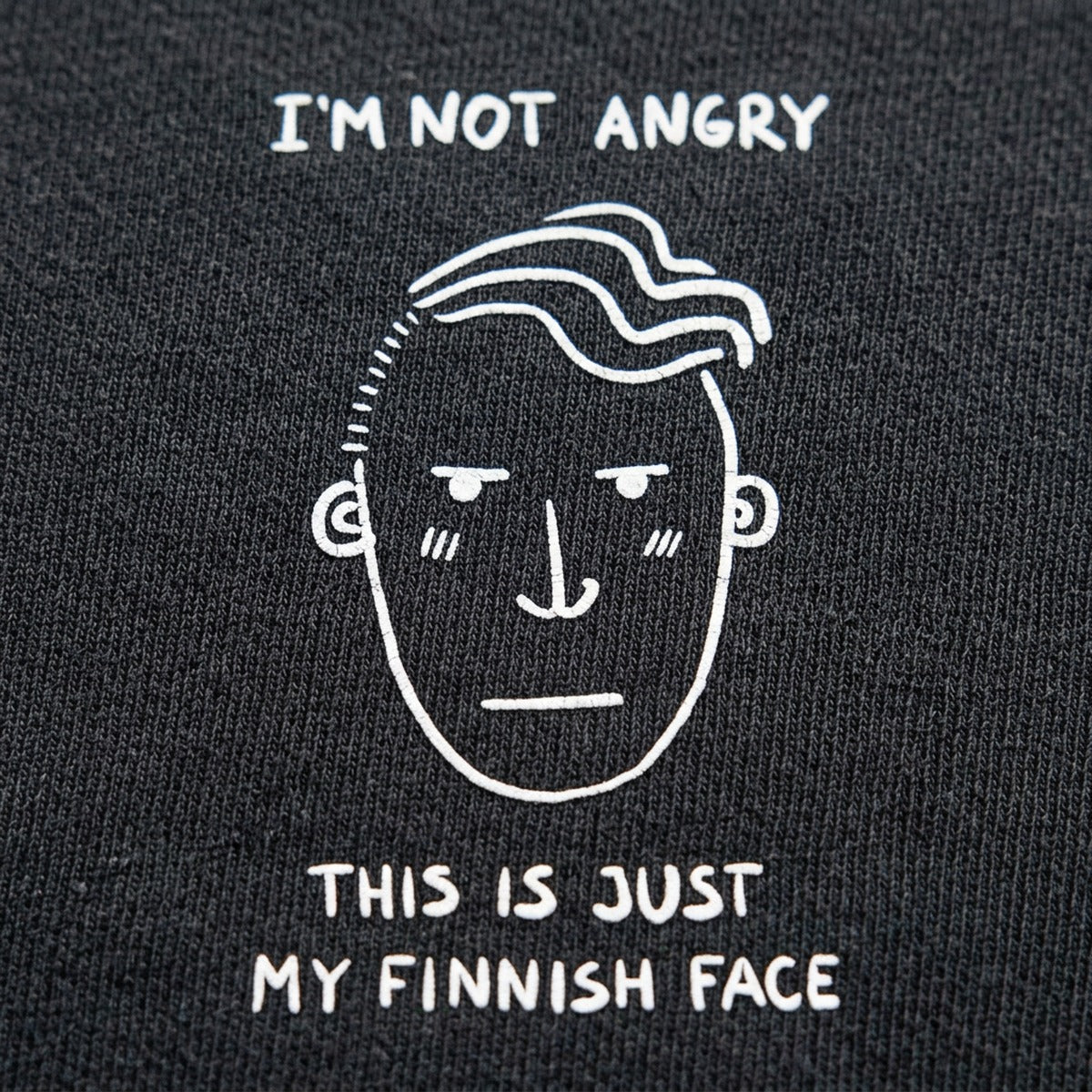 Close-up of dark grey Finnish Face Humour t-shirt print, I'm Not Angry This Is Just My Finnish Face, Very Finnish Problems