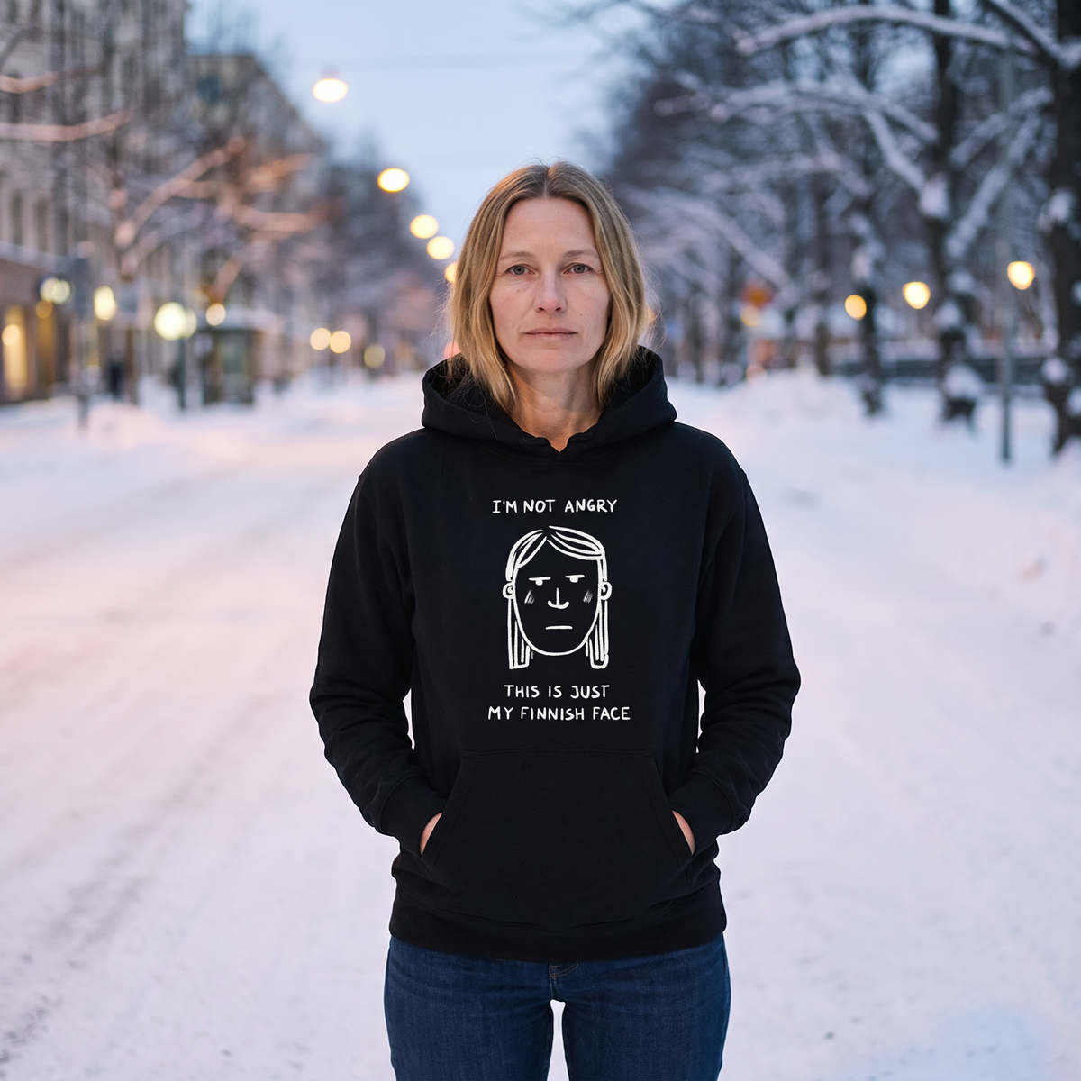 Finnish Face women's hoodie in black, worn by Elina on a snowy Helsinki street, Very Finnish Problems
