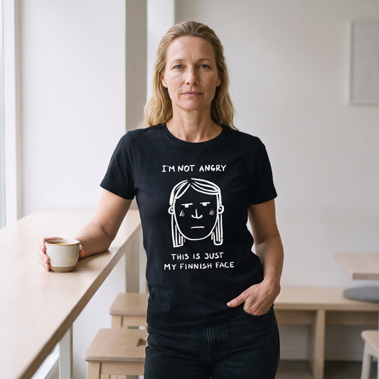 Finnish Face women's t-shirt in black, worn by Elina with a perfectly neutral expression at a cafe counter, Very Finnish Problems