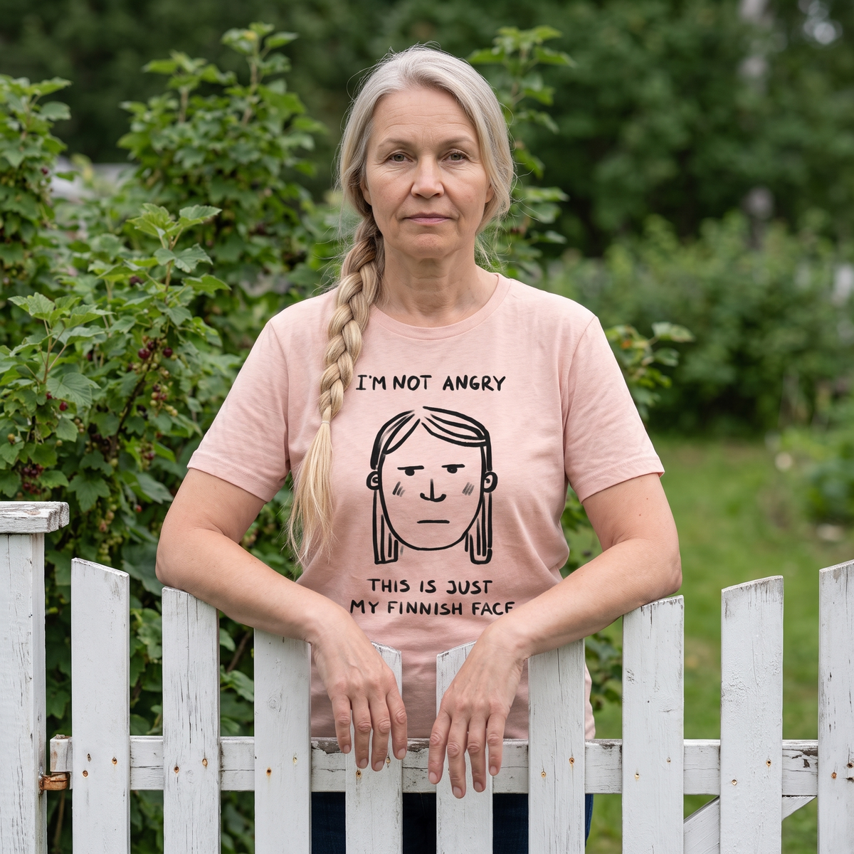 Finnish Face women's t-shirt in light pink, worn by Anneli expressionless at a garden gate, Very Finnish Problems