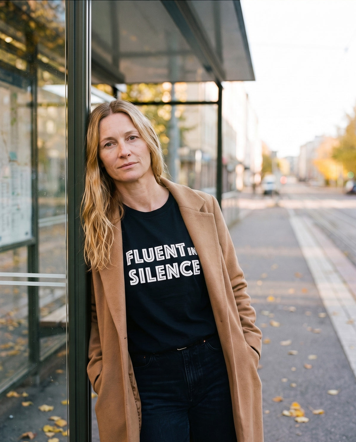 Fluent in Silence t-shirt in black, worn by Elina waiting at a Helsinki tram stop, Very Finnish Problems