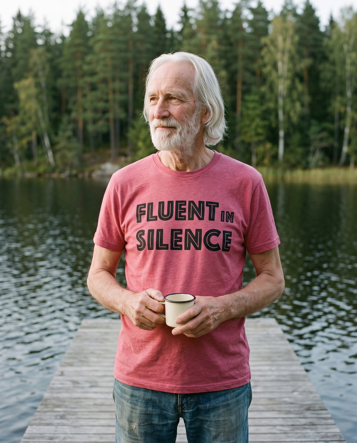 Fluent in Silence t-shirt in heather raspberry, worn by Pertti with a coffee on a lake jetty, Very Finnish Problems