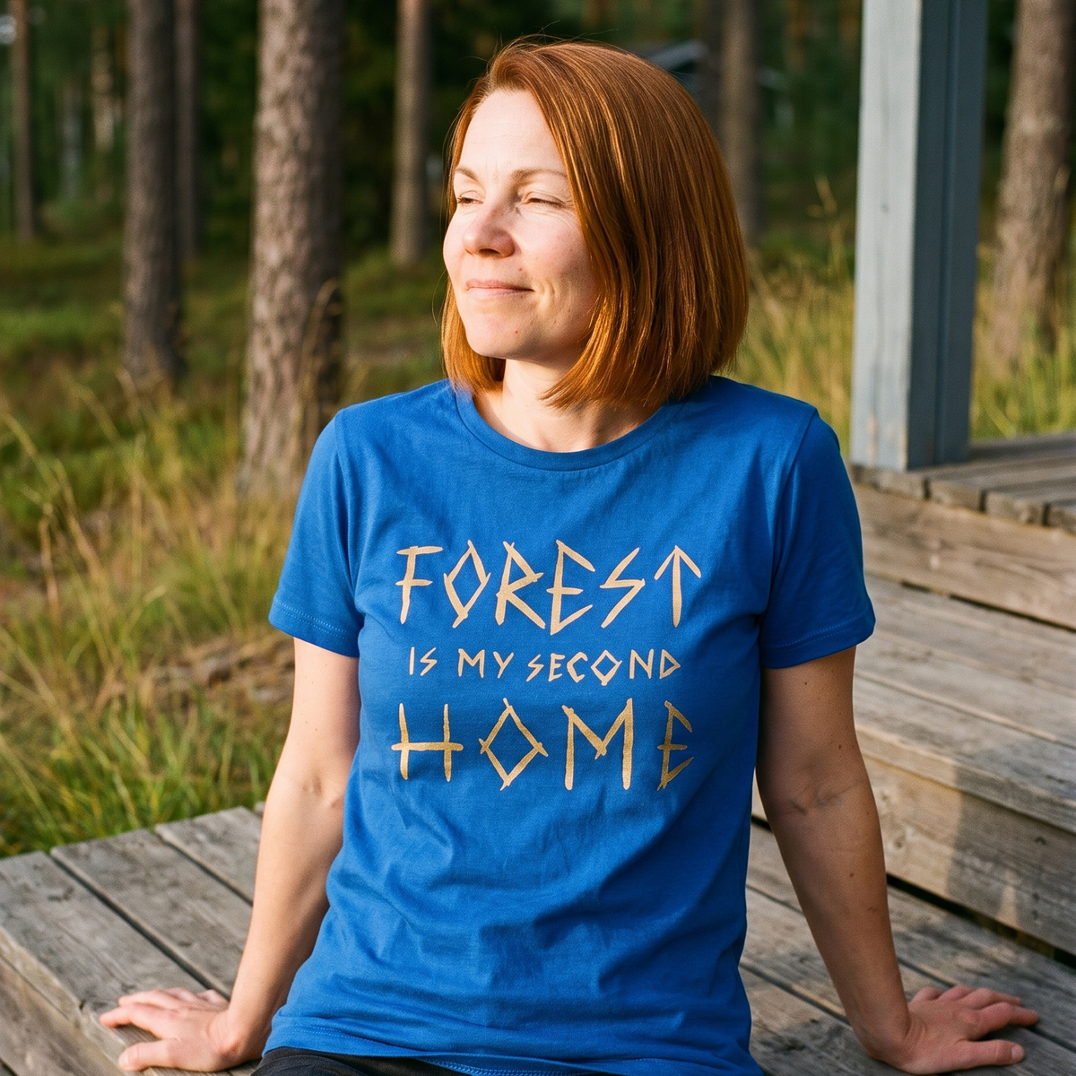 Forest Is Home t-shirt in true royal, worn by Sanna on the porch steps of a Finnish summer cottage, Very Finnish Problems