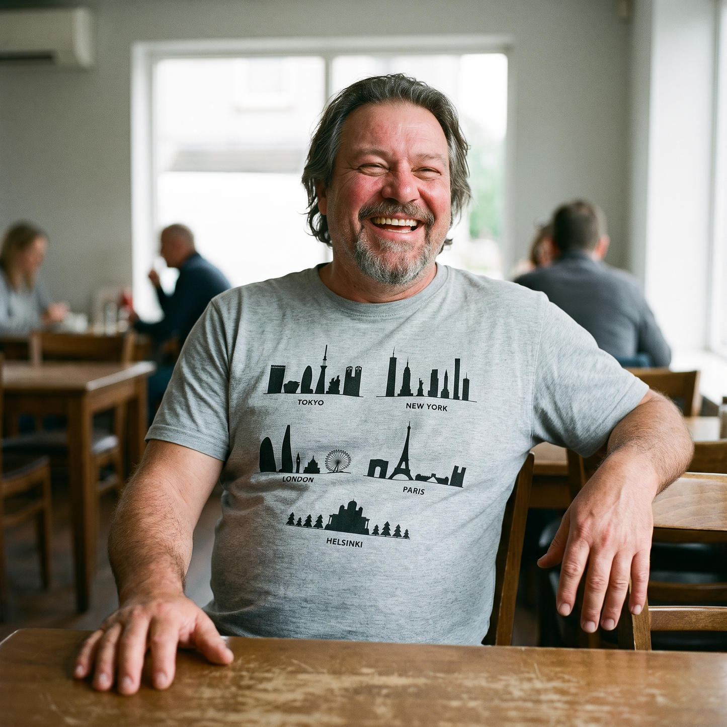 Helsinki Skyline t-shirt in grey, worn by Jojelli in a Finnish cafe, Very Finnish Problems