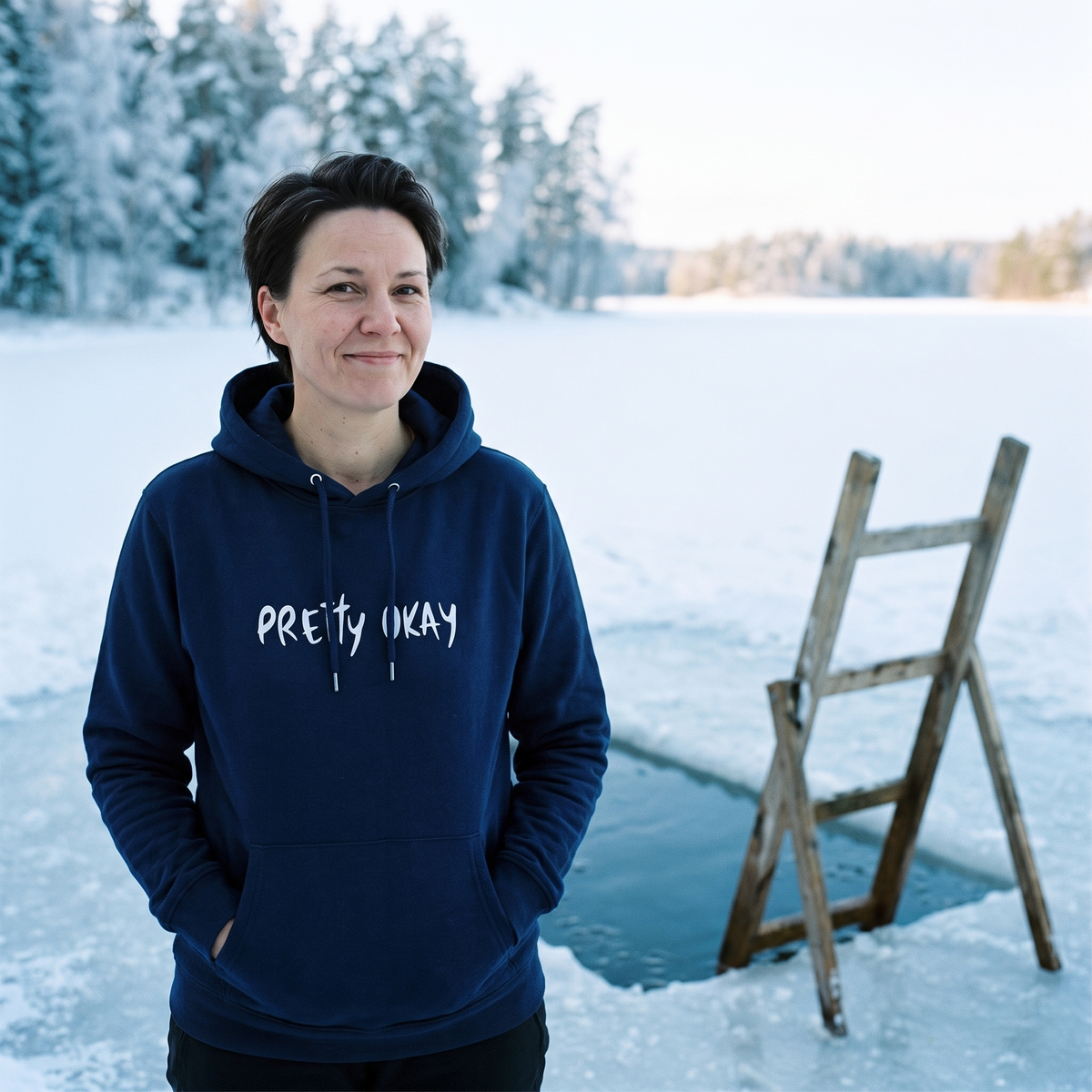 Pretty okay Finnish humour hoodie in navy, worn by Katja beside a cut ice swimming hole, Very Finnish Problems