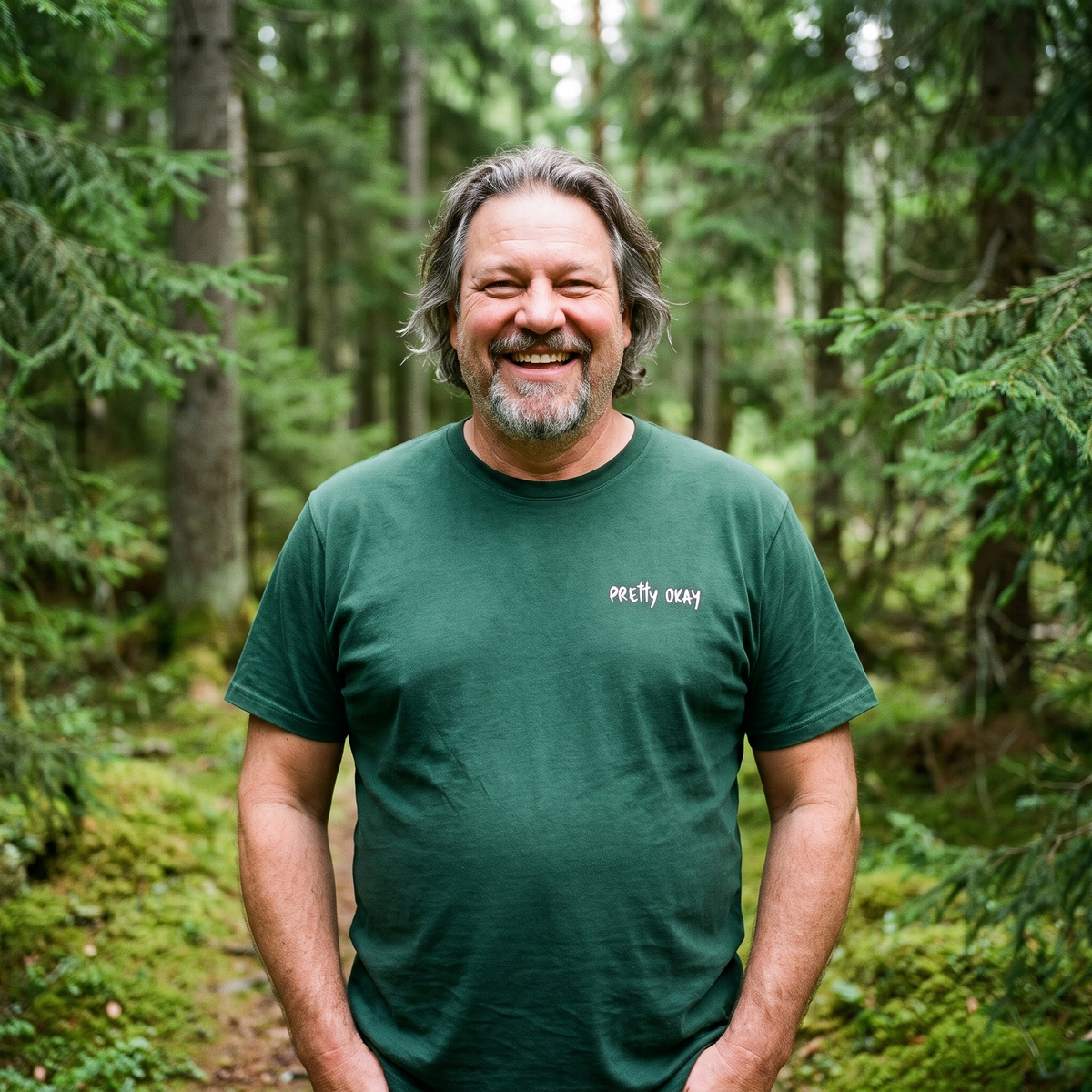 Pretty okay embroidered Finnish humour t-shirt in forest green, worn by Jojelli on a spruce forest path, Very Finnish Problems