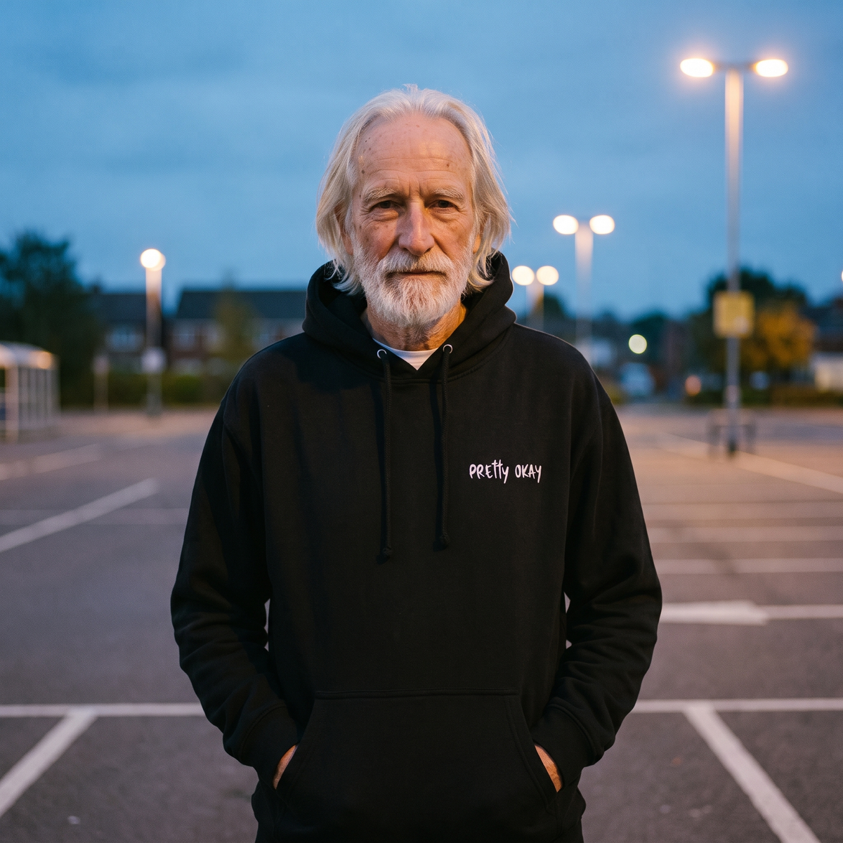Pretty okay embroidered Finnish humour hoodie in black, worn by Pertti in a car park at dusk, Very Finnish Problems