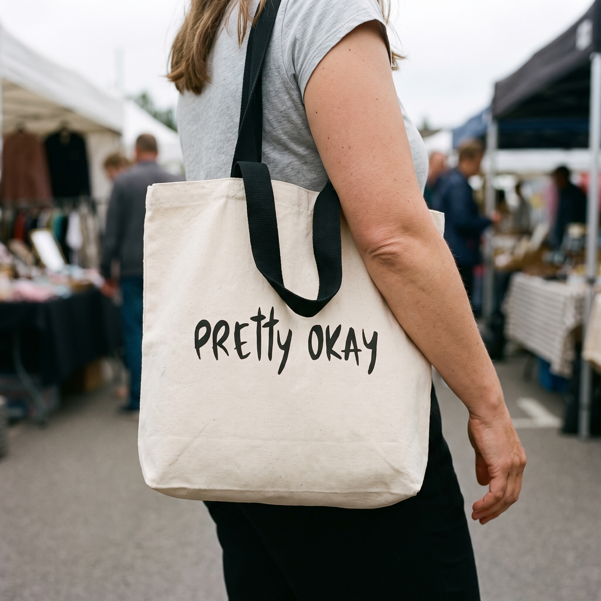 Pretty okay Finnish humour tote bag with black handles, carried through an outdoor market, Very Finnish Problems
