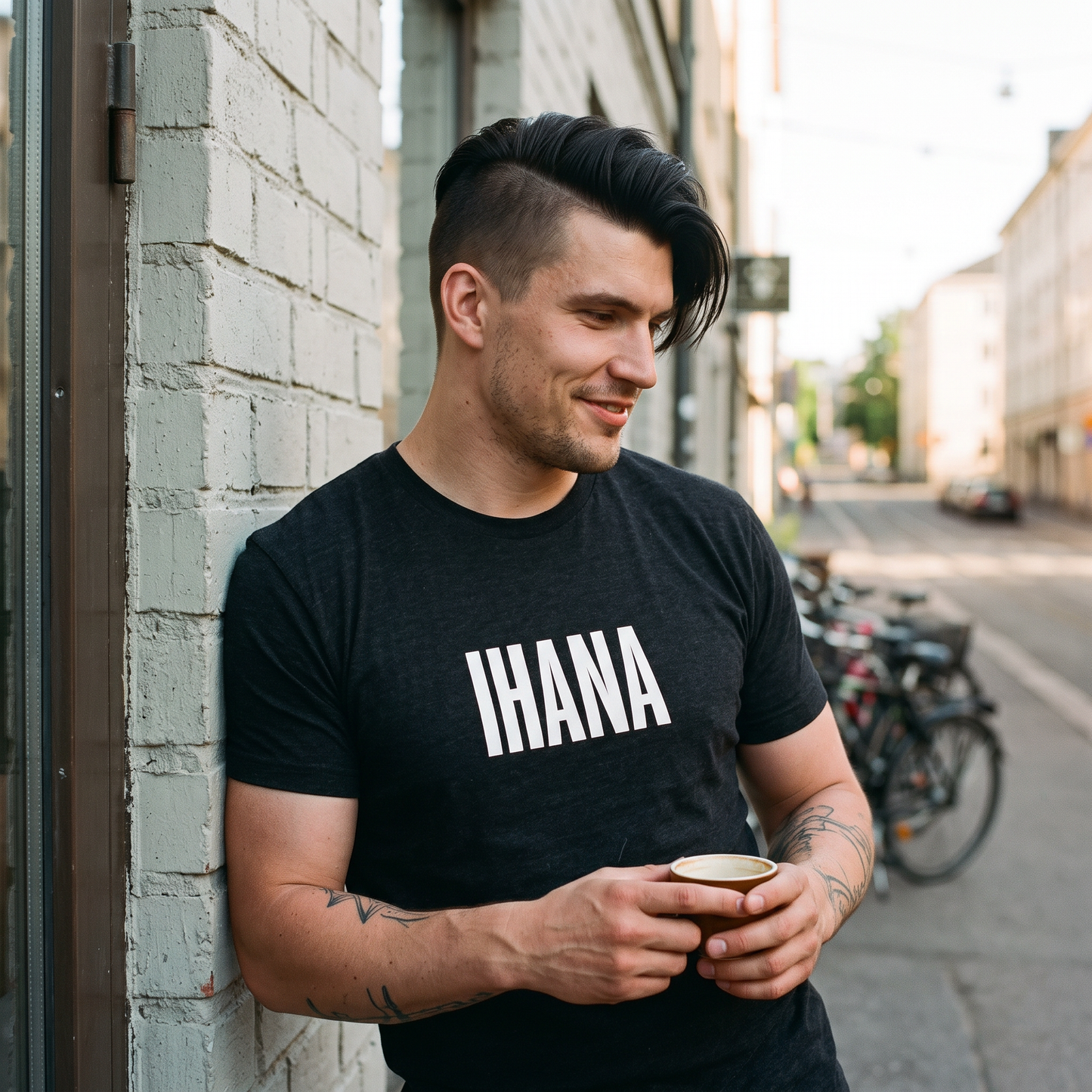 IHANA Finnish t-shirt in black heather, worn by a man with a coffee on a Kallio street corner in Helsinki, Very Finnish Problems