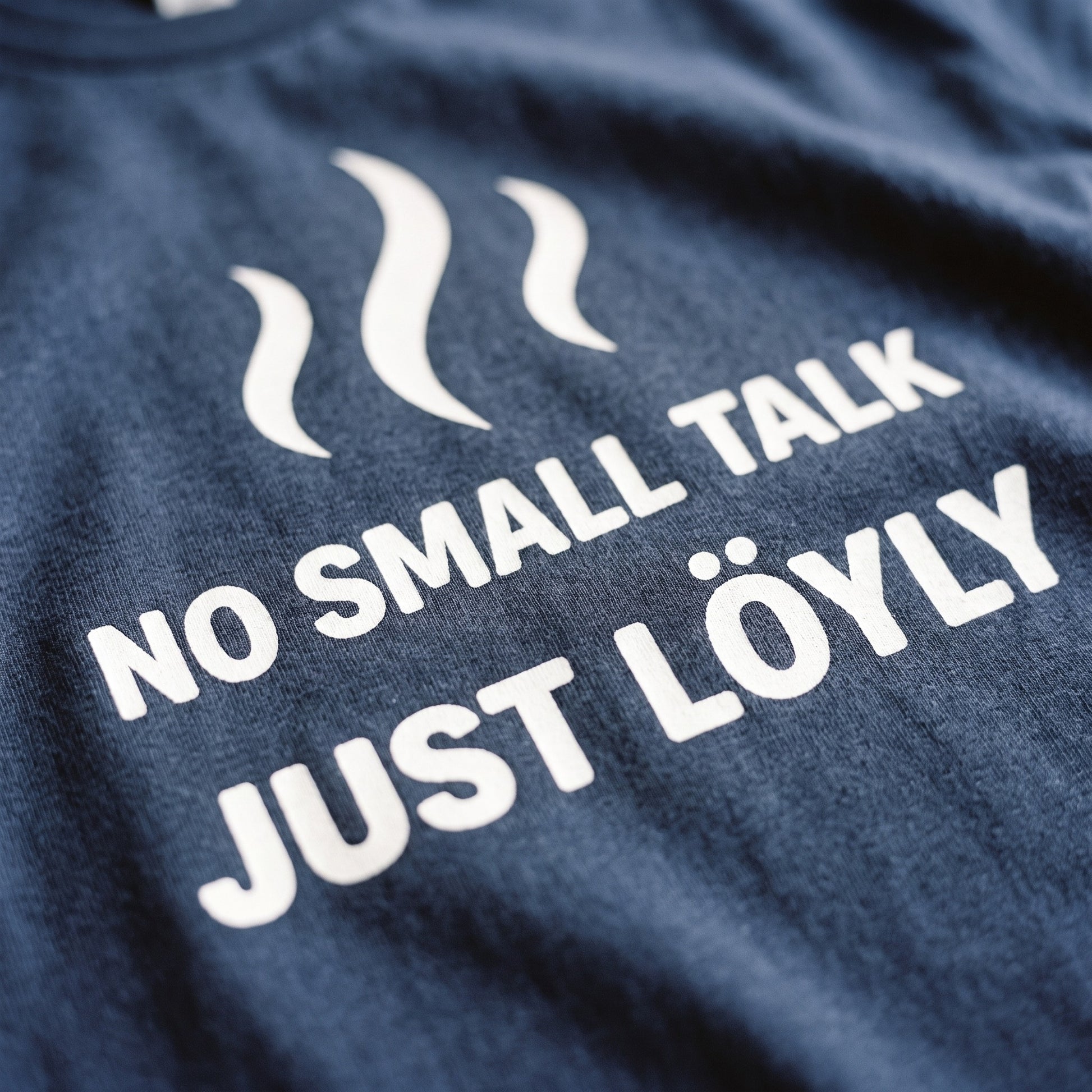 Close-up of the No Small Talk Just Löyly print on navy t-shirt fabric, Very Finnish Problems
