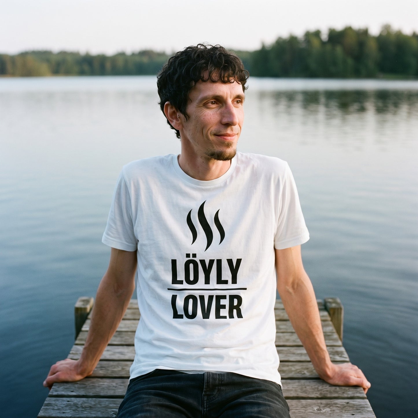 Löyly Lover t-shirt in white, worn by a man sitting on a jetty with his feet in a Finnish lake, Very Finnish Problems